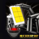 Close-up of a car air freshener with yellow square panels and red light, held by a hand against a dark background.

